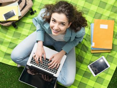 Studentin mit Laptop auf einer Wiese
