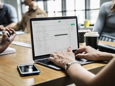 Person arbeitet am Laptop während eines Meetings
